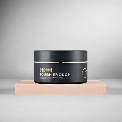 BARBER BARBER Tough Enough Strong Hold Styling Clay 100g - zwart potje op beige blok, grijze studio