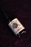 By Elementum Mollis Astrum Beard Oil - flesje liggend op paars fluweel met etiket in beeld